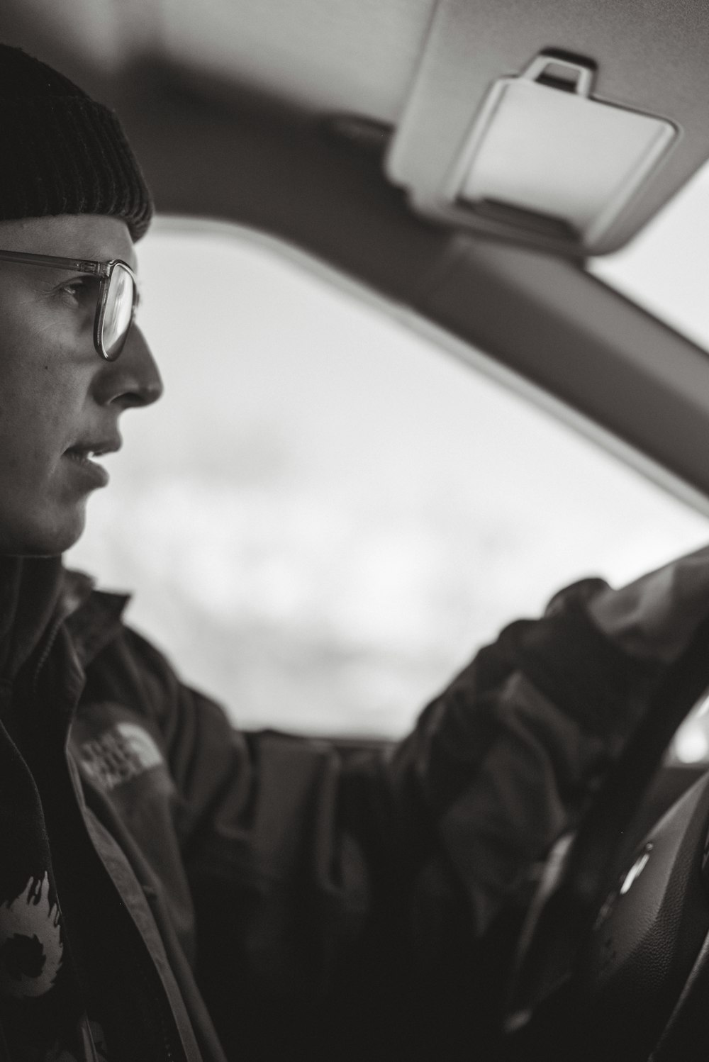 a man driving a car wearing a hat and glasses