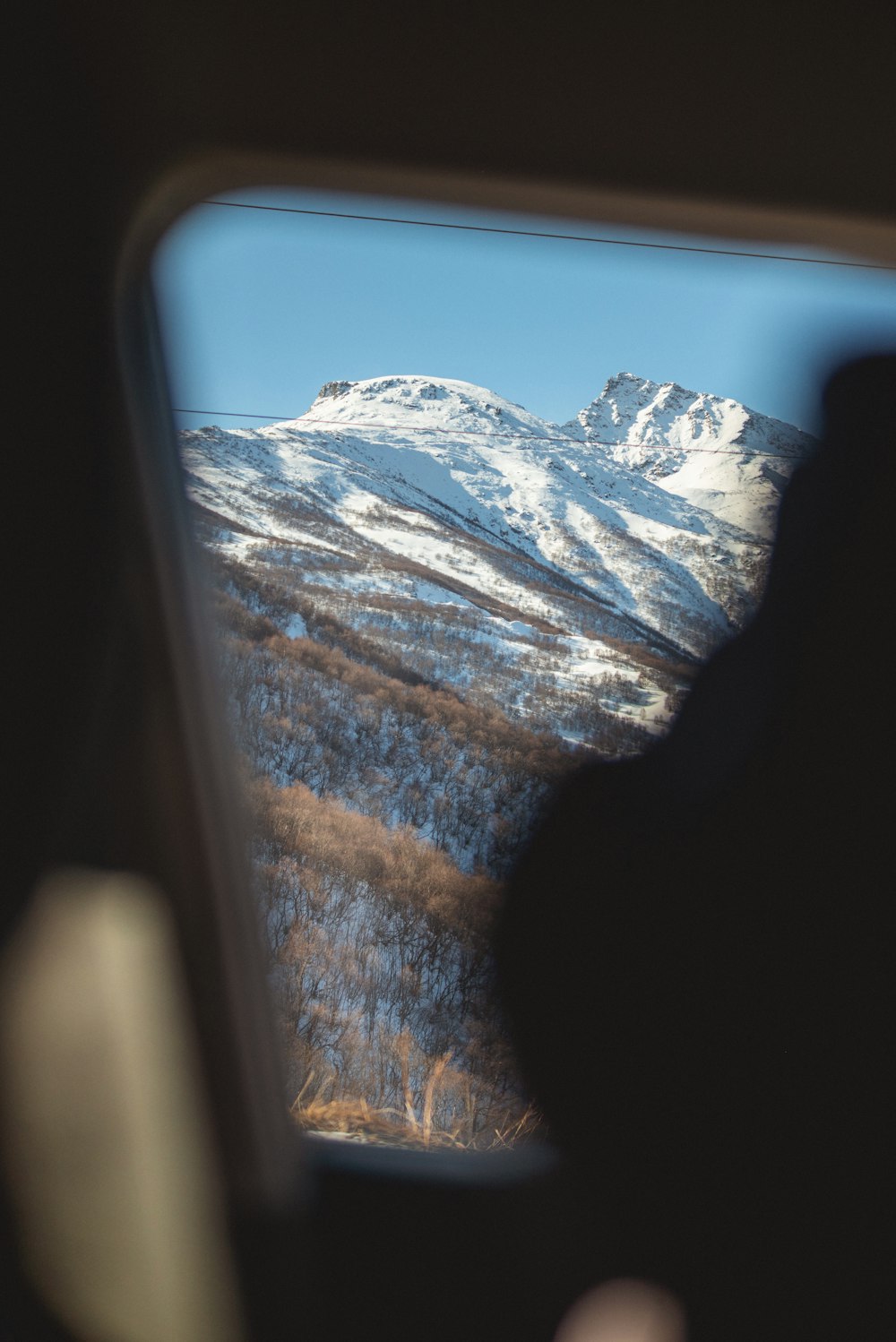 a view of a snowy mountain from inside a vehicle