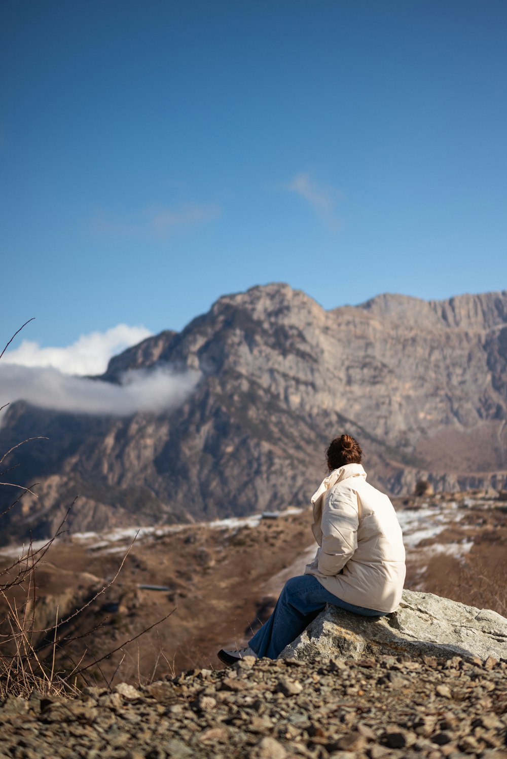 a woman sitting on a rock looking at the mountains