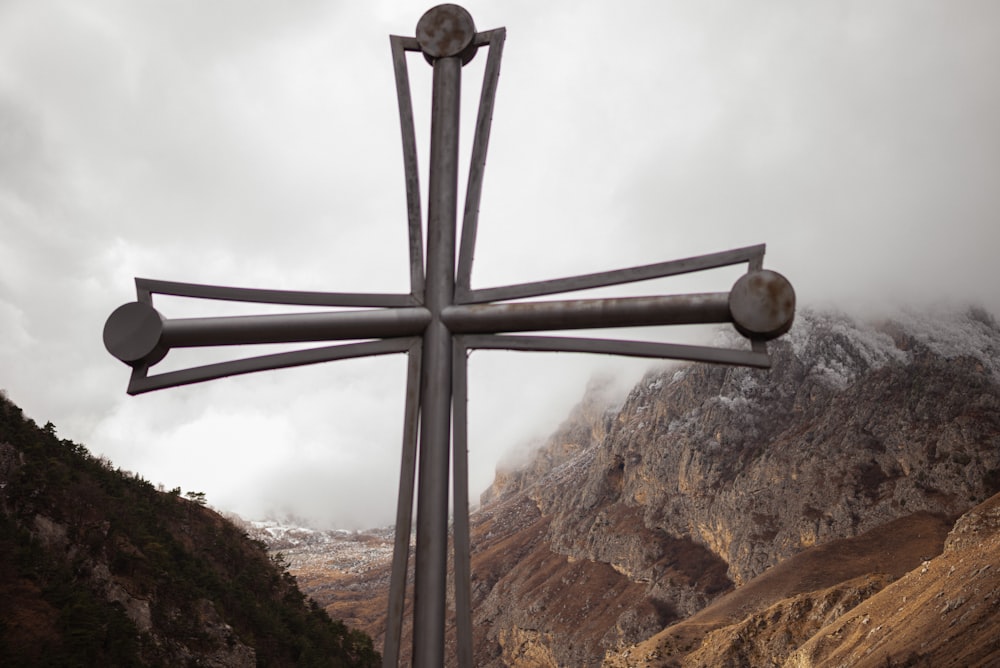 a large metal cross on top of a mountain