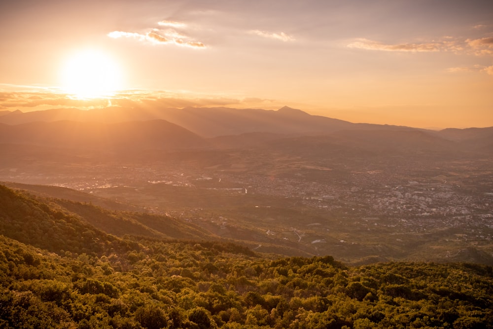 the sun is setting over the mountains in the distance