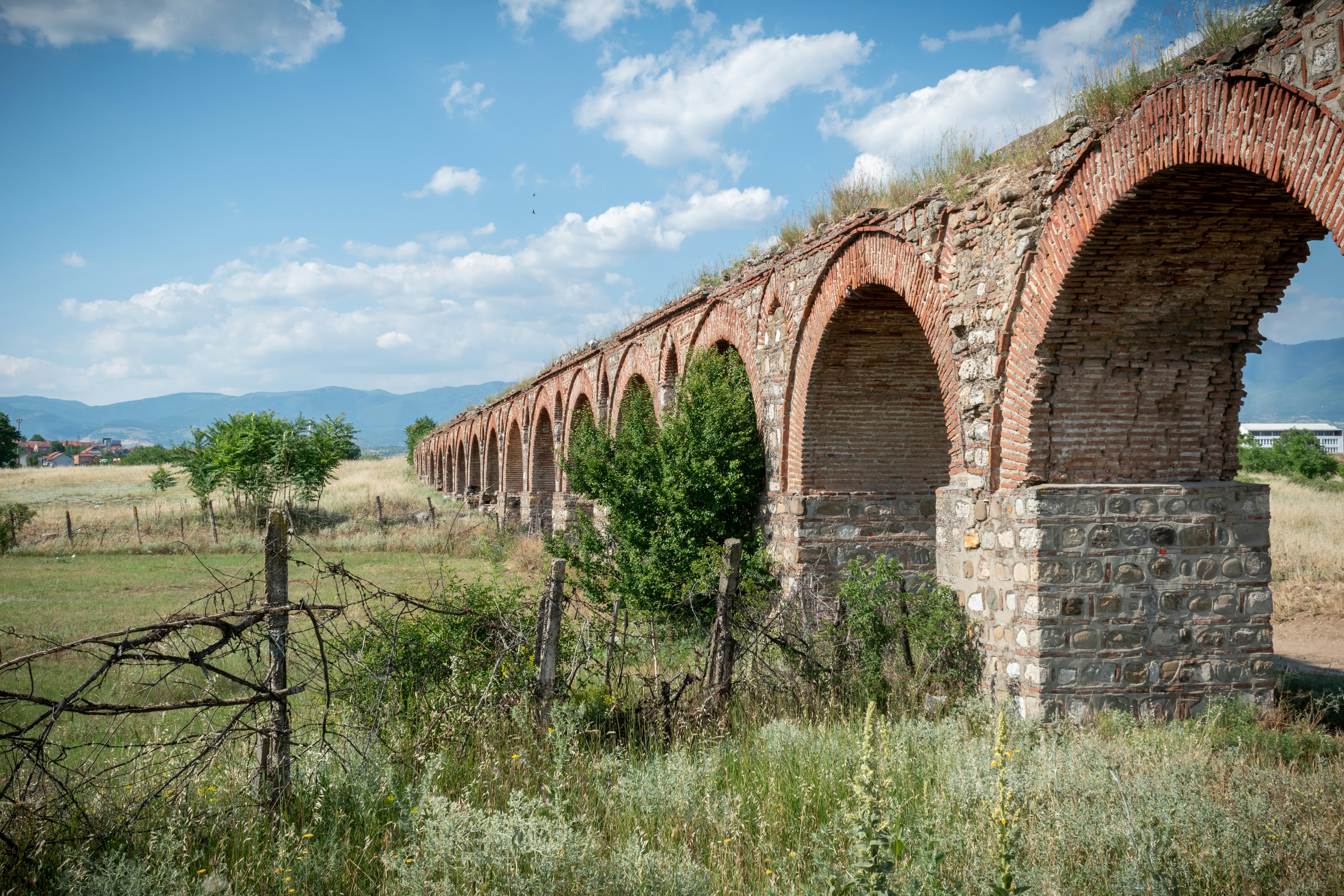 an old brick bridge with arches in a field