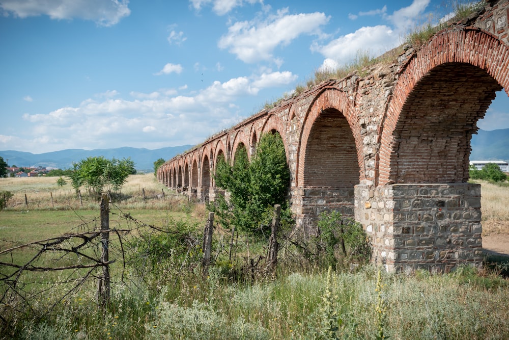an old brick bridge with arches in a field