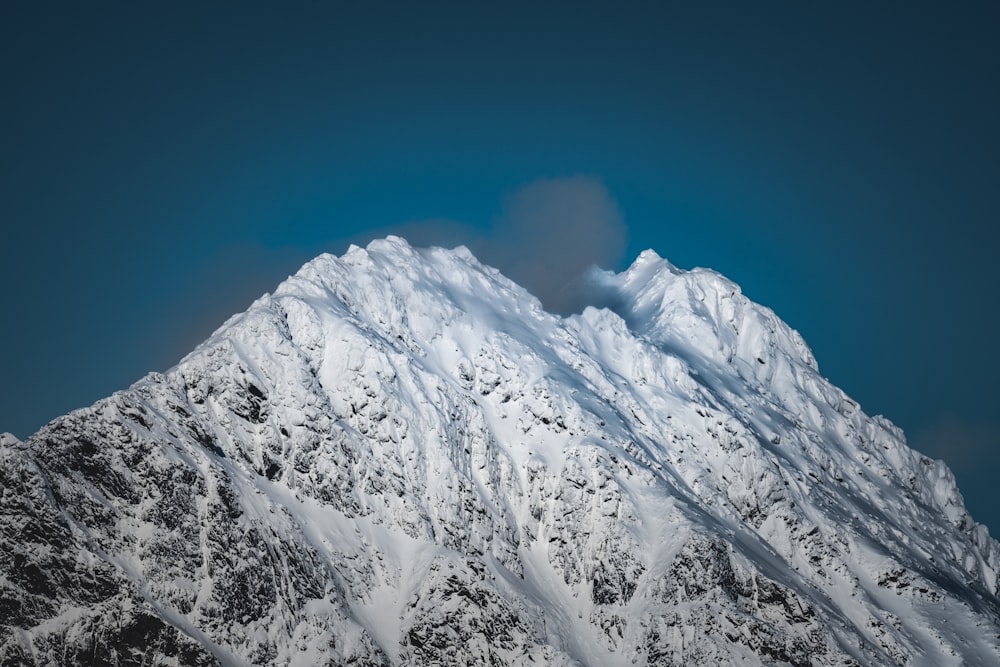 a very tall snow covered mountain under a blue sky