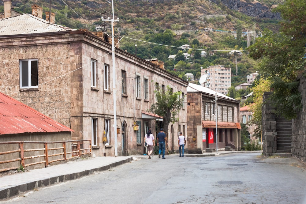 a group of people walking down a street next to buildings