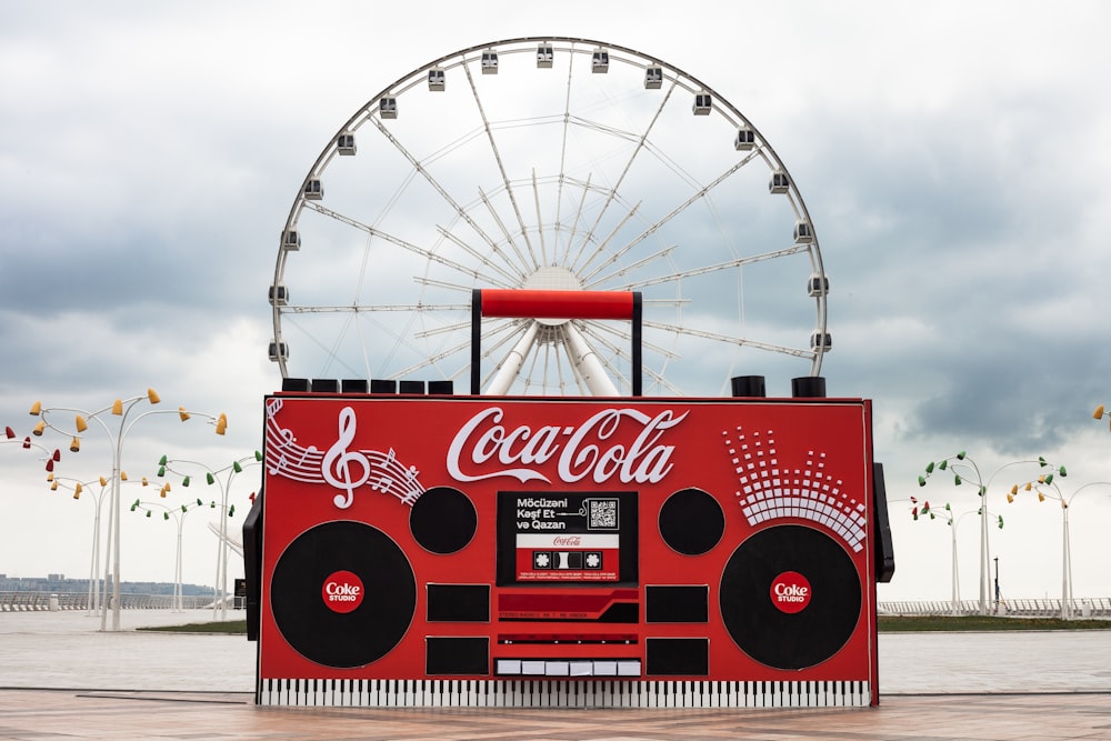 a coca cola machine with a ferris wheel in the background
