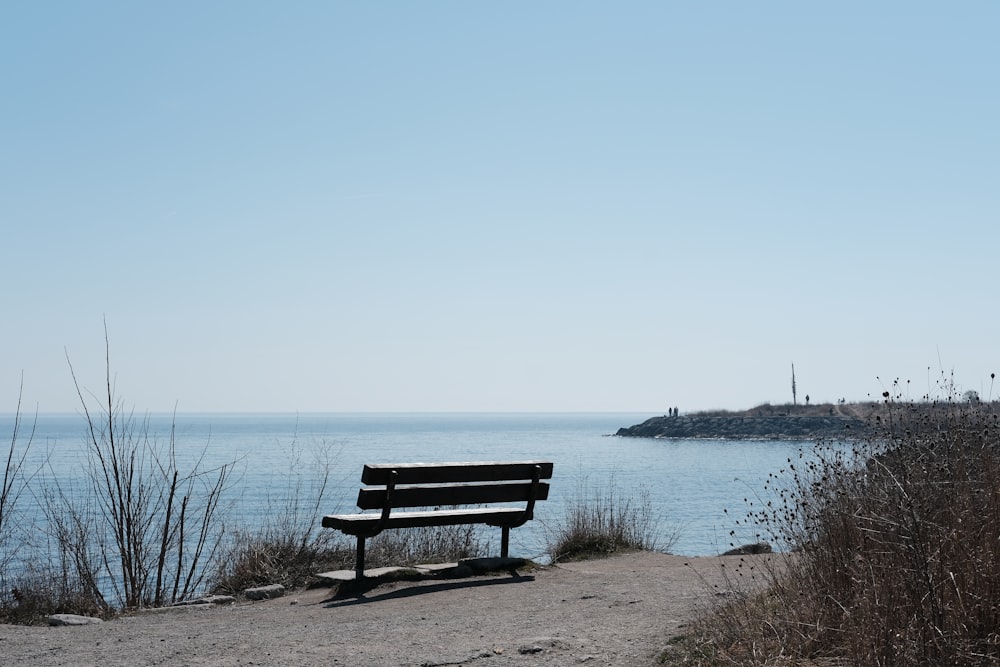 a wooden bench sitting on top of a sandy beach