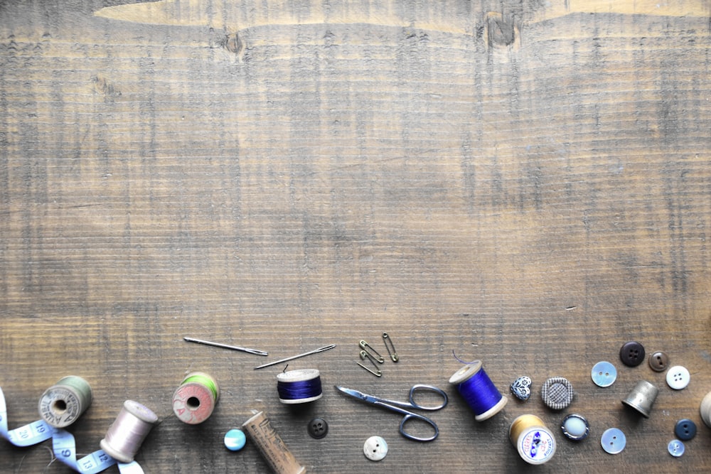 a wooden table topped with lots of different types of thread
