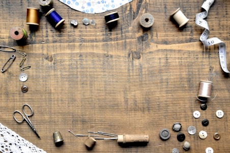 a wooden table topped with lots of sewing supplies