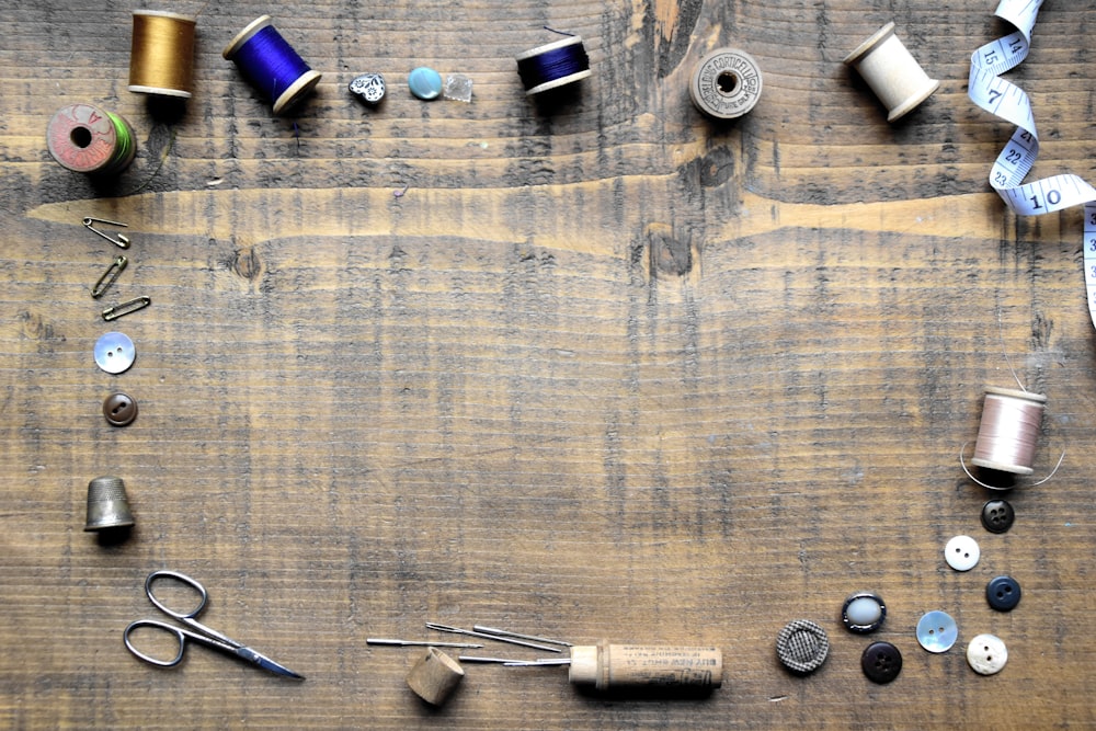 a wooden table topped with lots of different types of thread