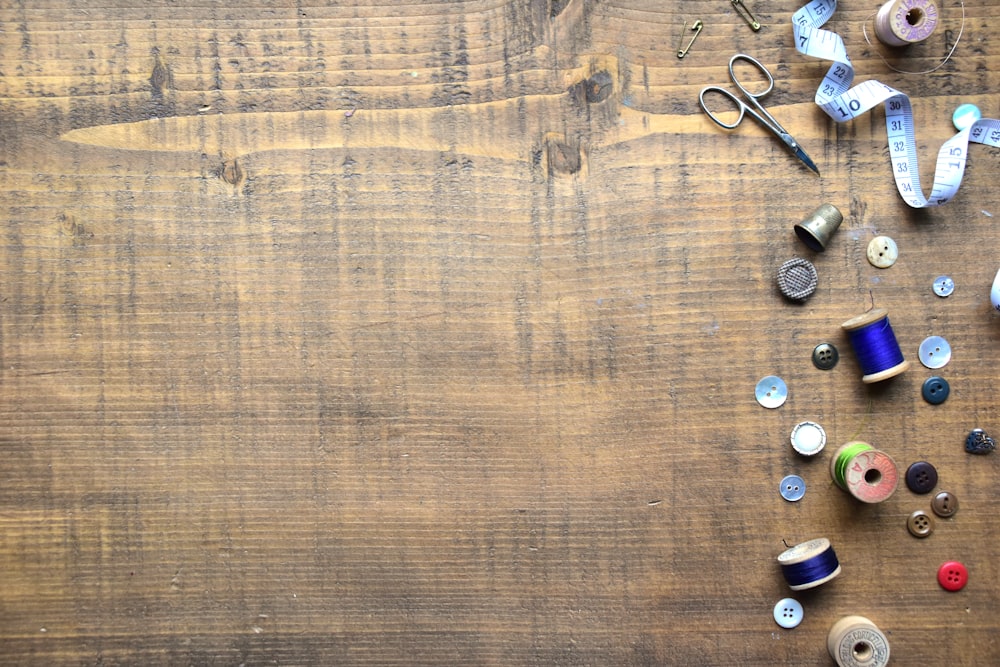 a wooden table topped with lots of spools of thread