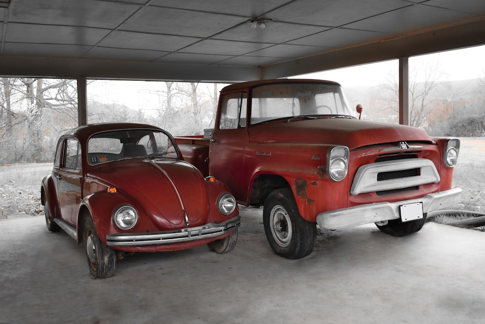 two old trucks are parked in a garage