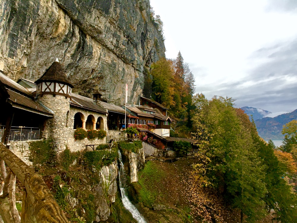 a building on the side of a cliff with a waterfall