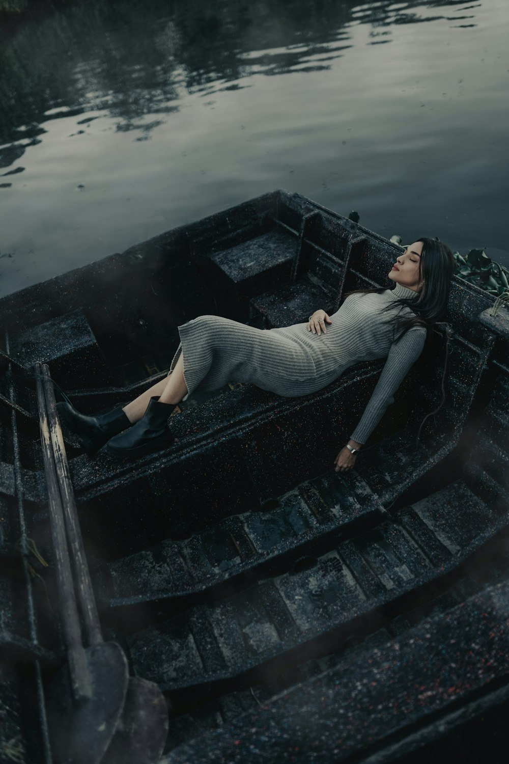 a woman laying on top of a boat in a body of water