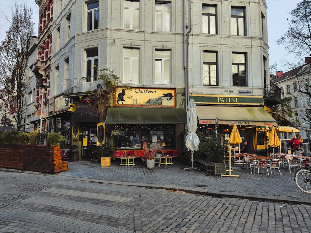 a street corner with tables and chairs and a building in the background