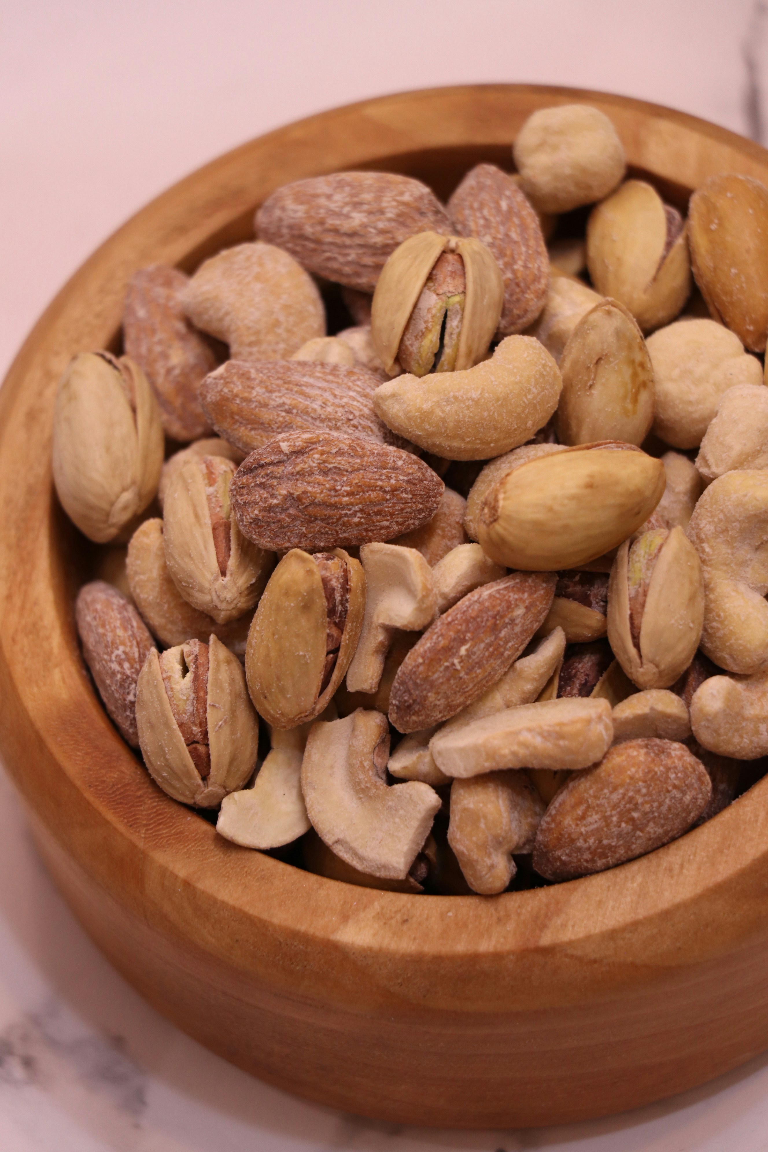 Assorted mixed nuts including almonds cashews and walnuts in a wooden bowl