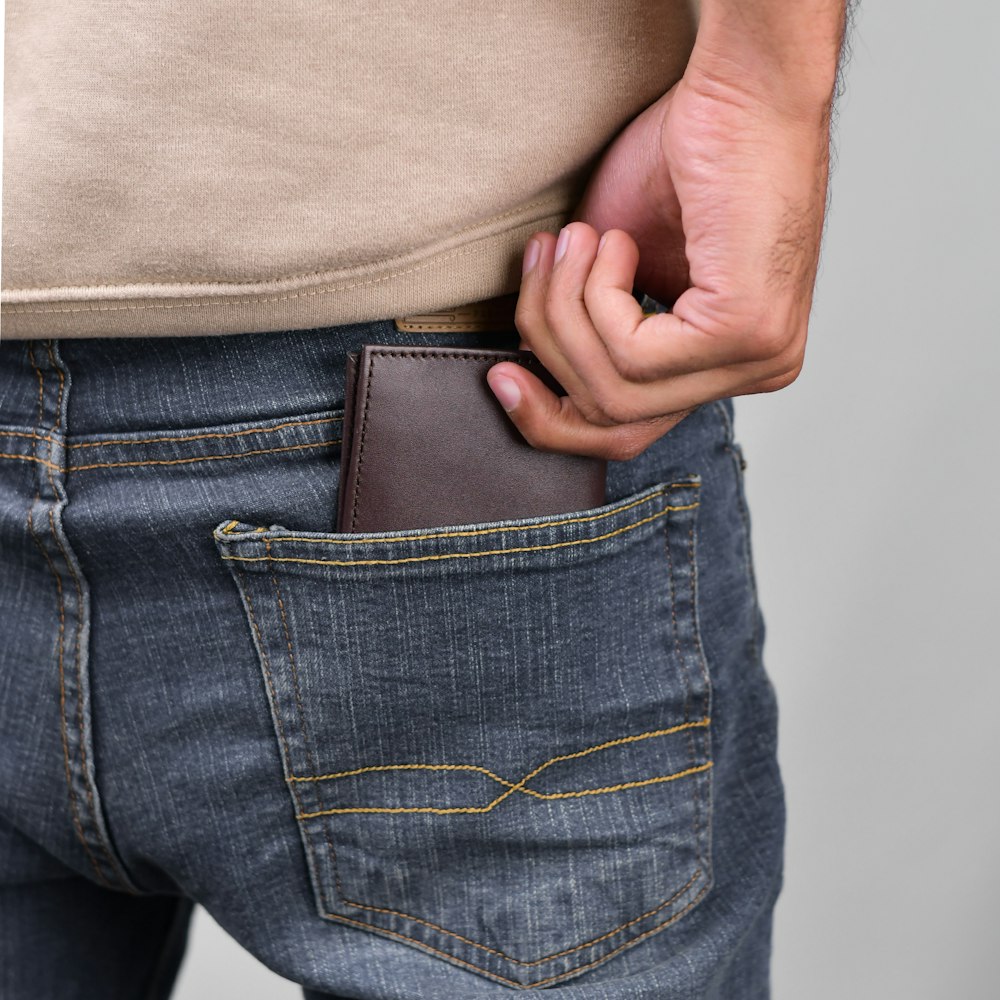 a man is holding his wallet in his pocket
