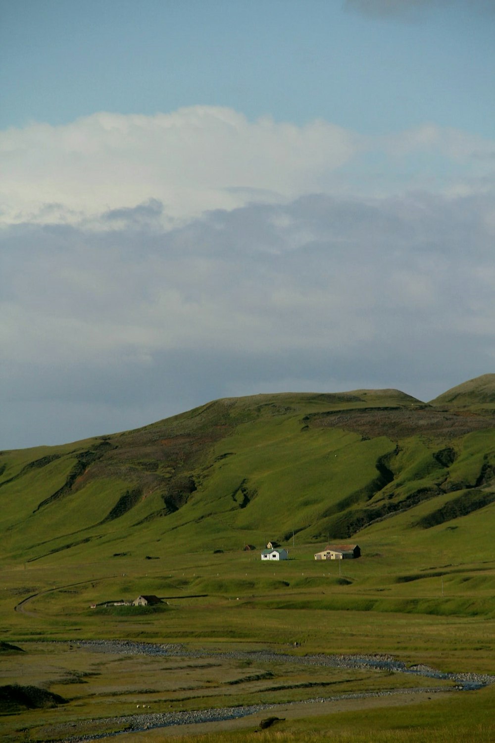 a grassy hill with a stream running through it