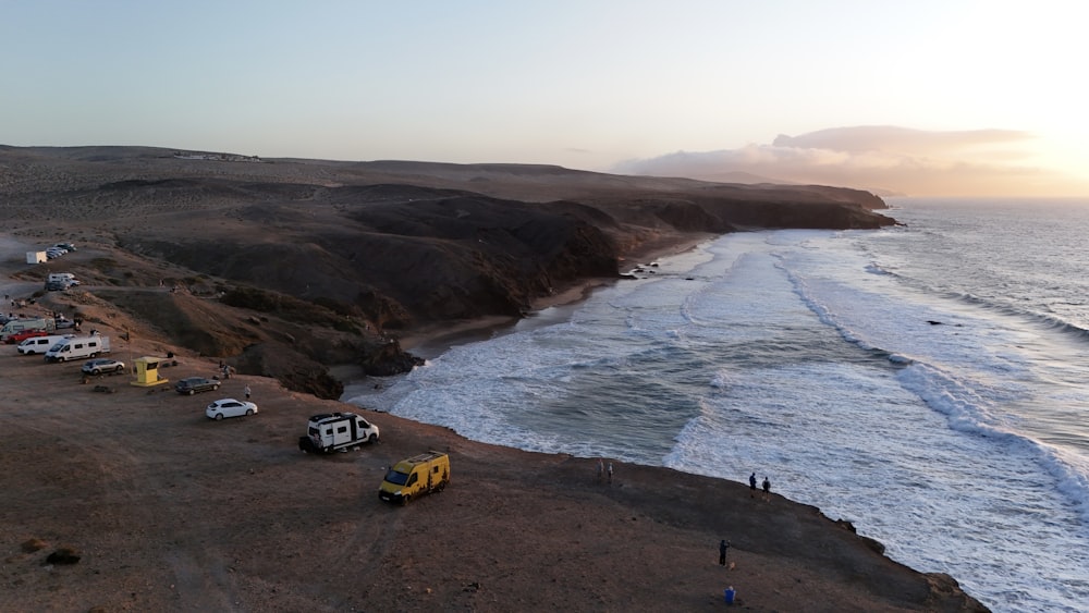 a group of cars parked on a beach next to the ocean