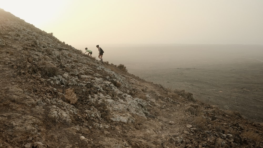 two people walking up a hill with a dog