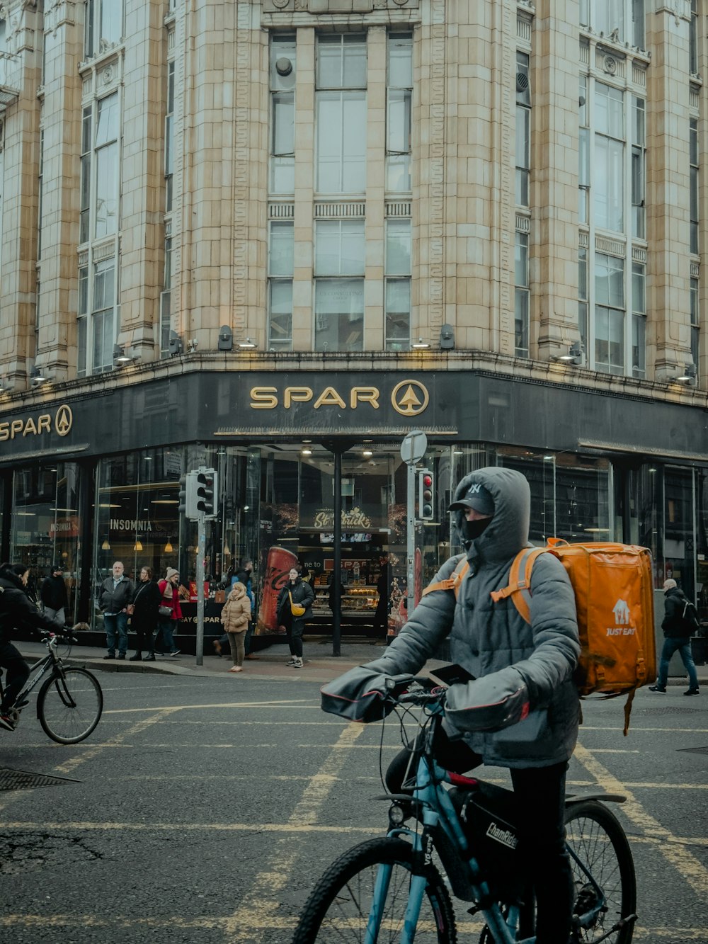 a man riding a bike down a street next to a tall building