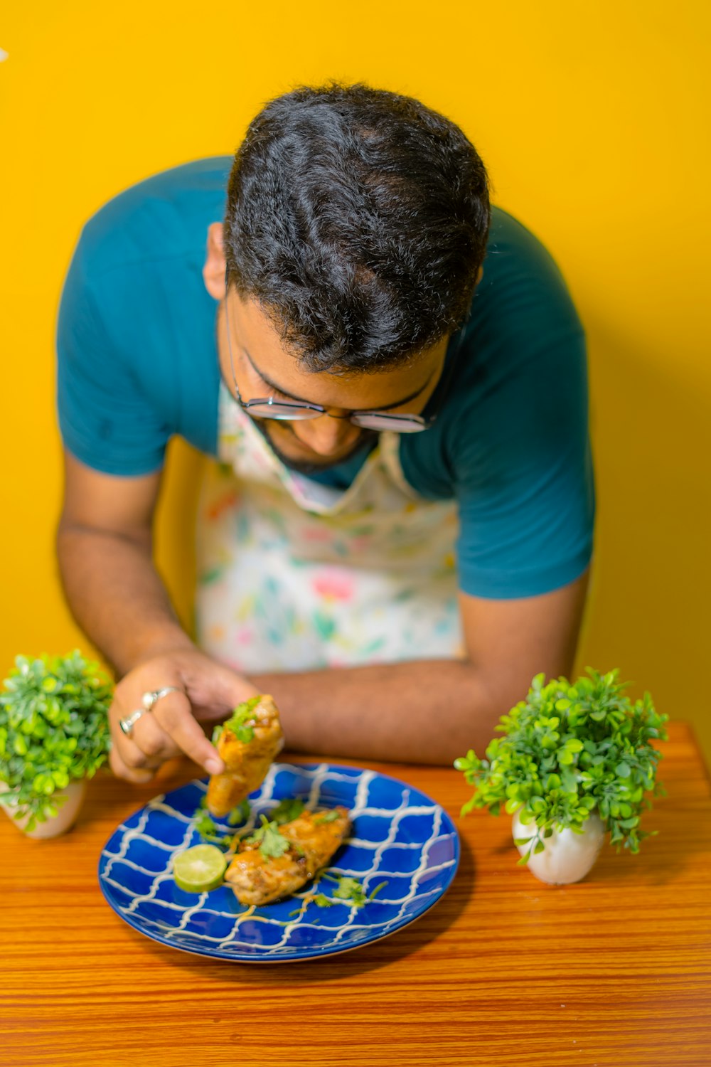 a man in glasses is eating food on a blue plate