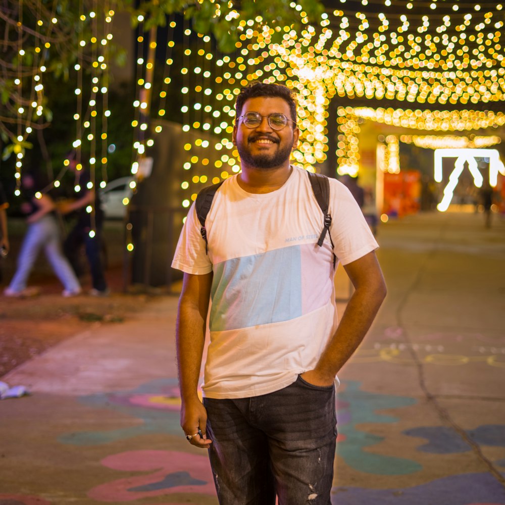 a man standing on a sidewalk in front of some lights