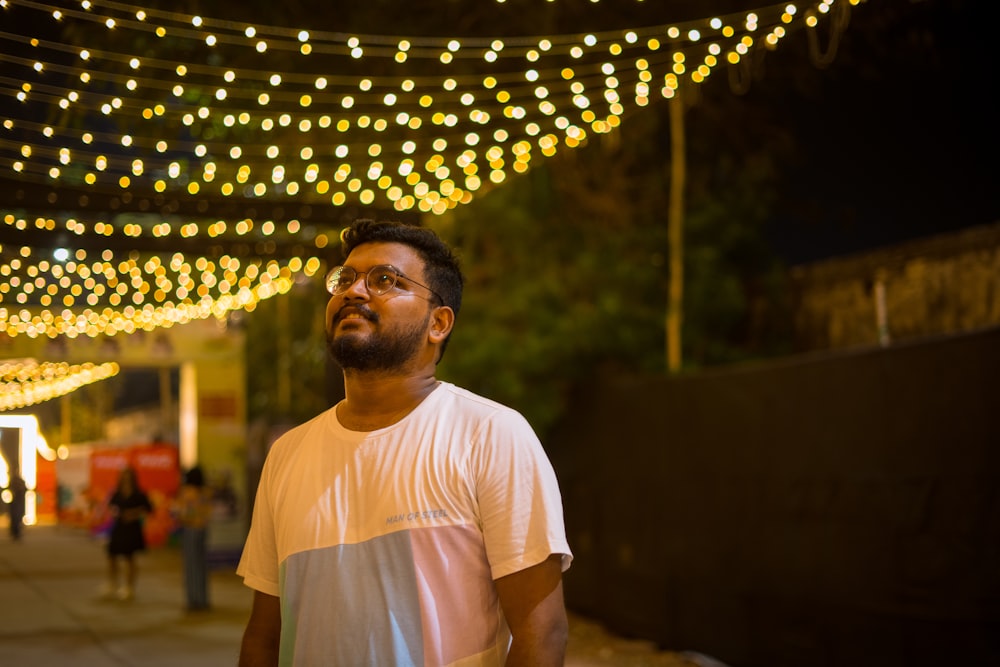 a man standing in front of a string of lights