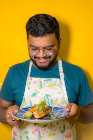 a man in an apron holding a plate of food