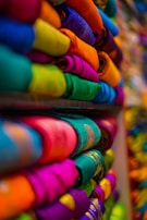 a bunch of colorful t - shirts are stacked on a shelf