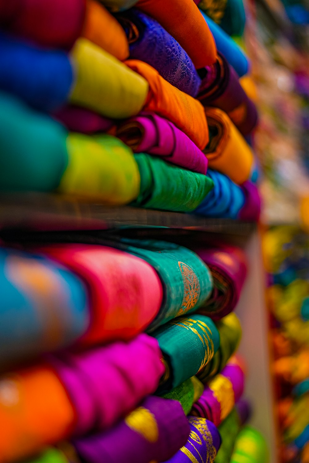 a bunch of colorful t - shirts are stacked on a shelf