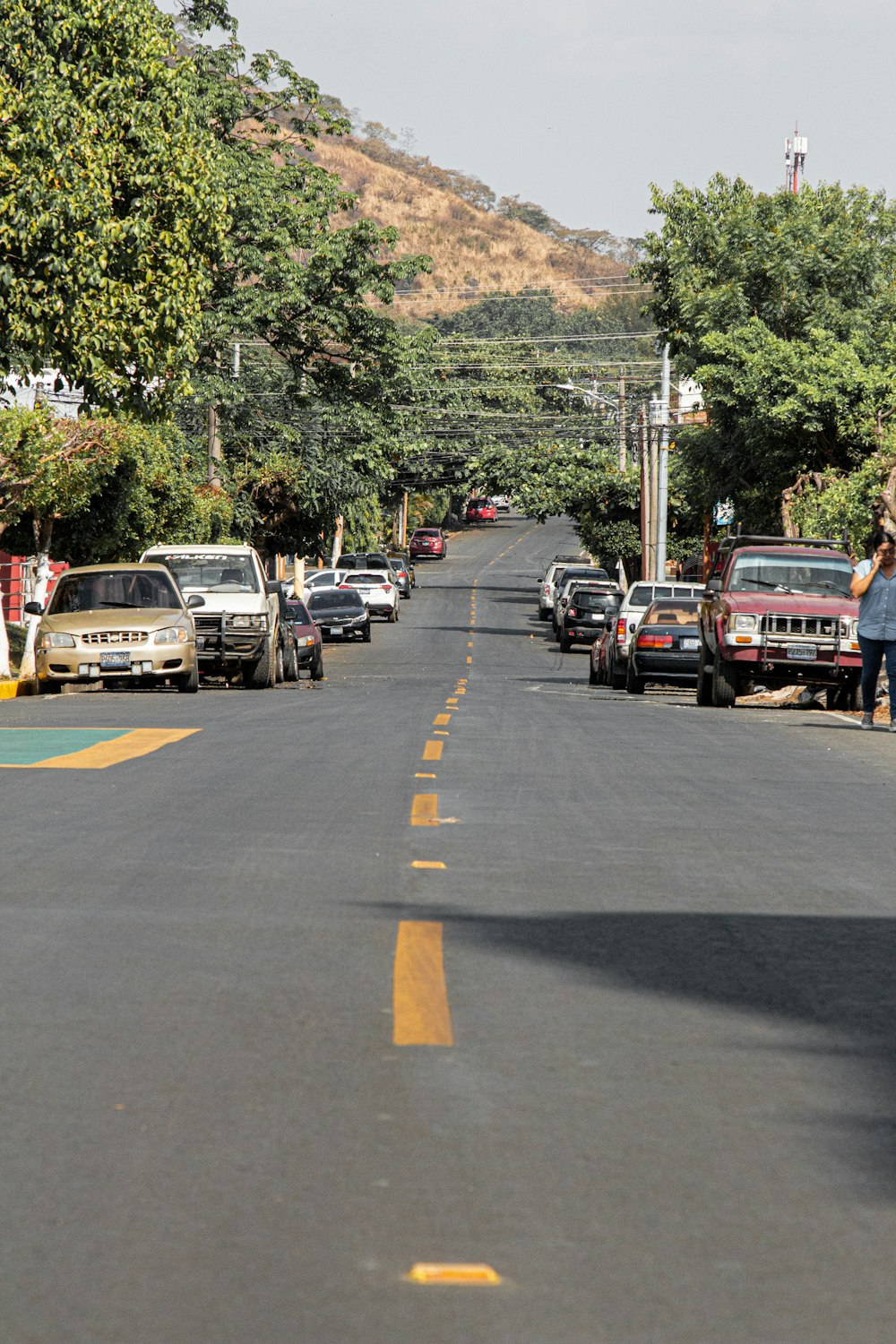 a woman standing on the side of a road next to parked cars