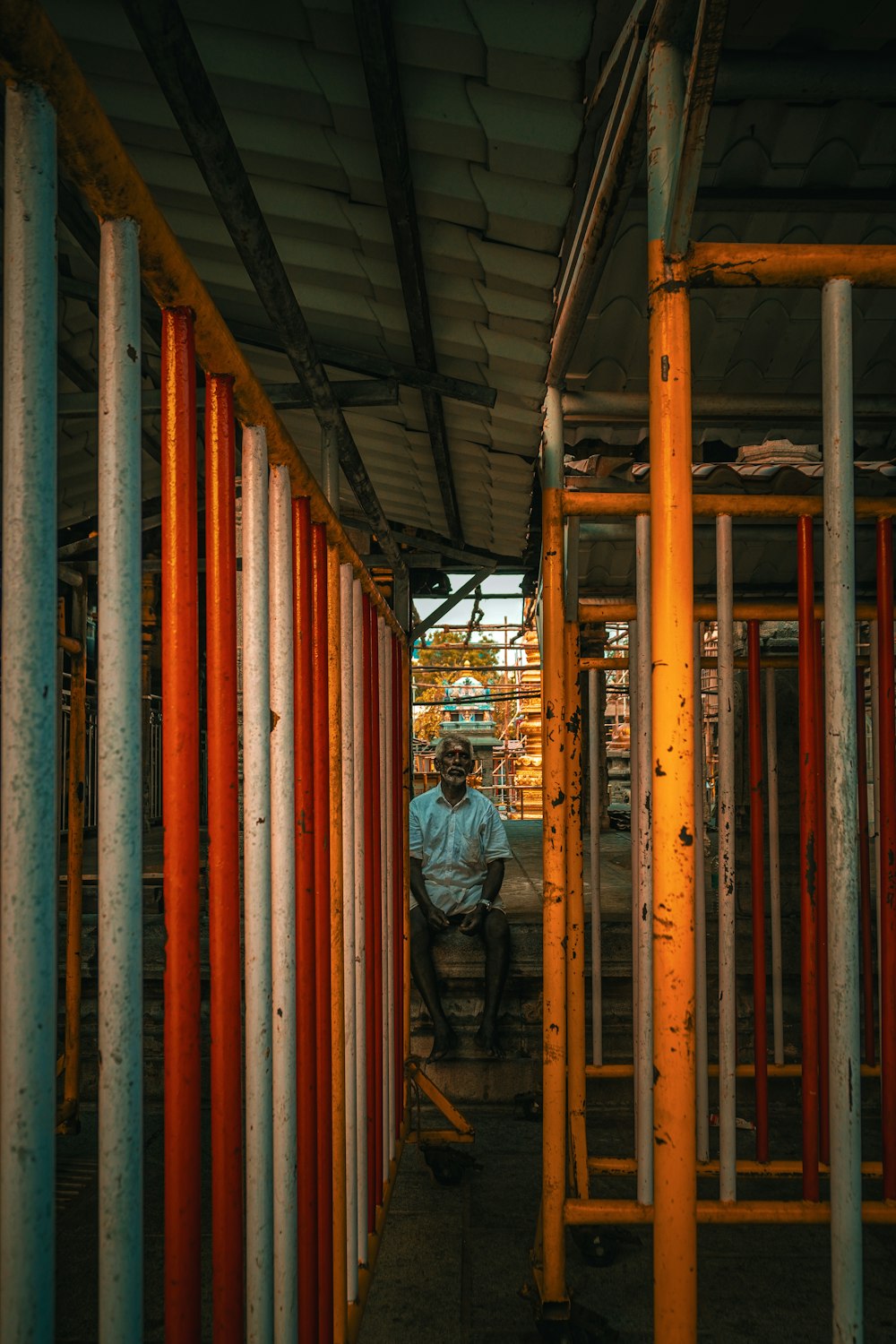 a man sitting in a room filled with orange and white pipes