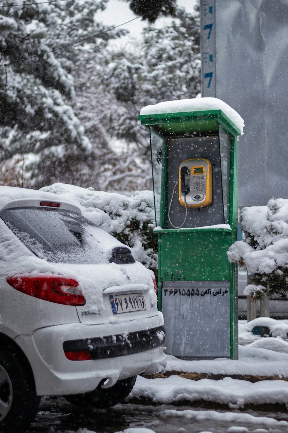 a parking meter covered in snow next to a white car