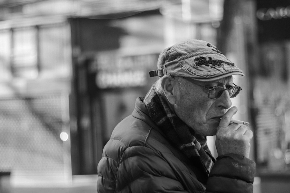 a black and white photo of a man in a hat talking on a cell phone