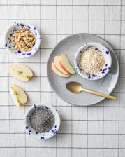 a bowl of oatmeal, apple slices, and spoon on a plate