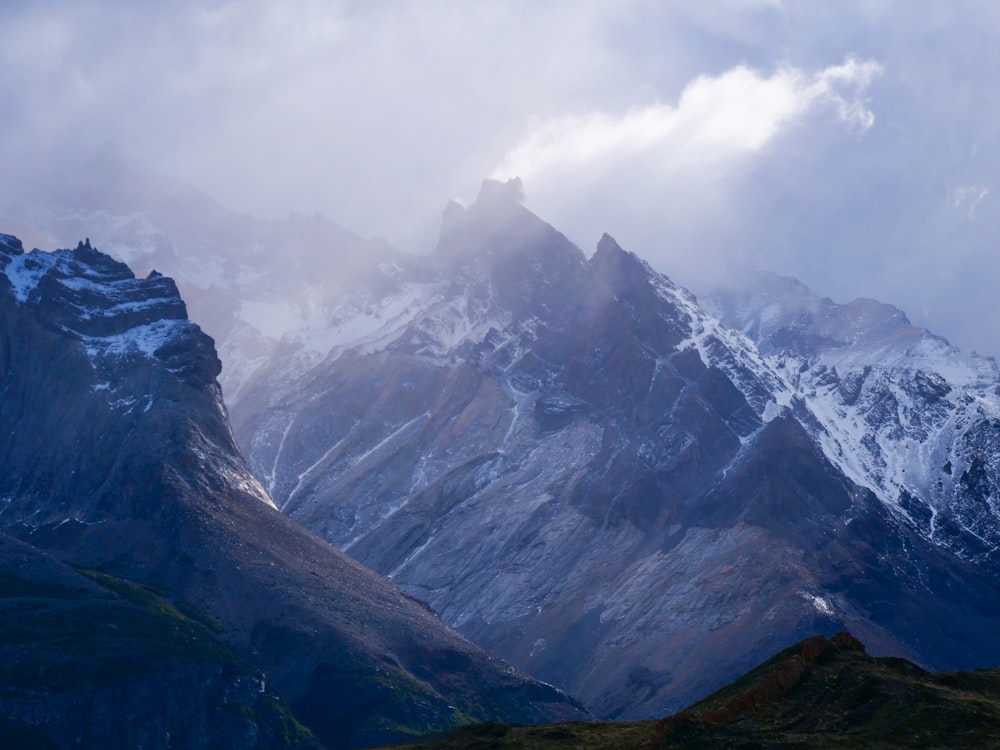 a mountain range covered in snow under a cloudy sky