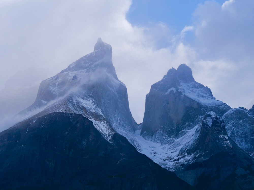 a group of mountains covered in snow under a cloudy sky