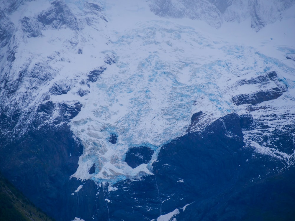 a large mountain covered in snow next to a river