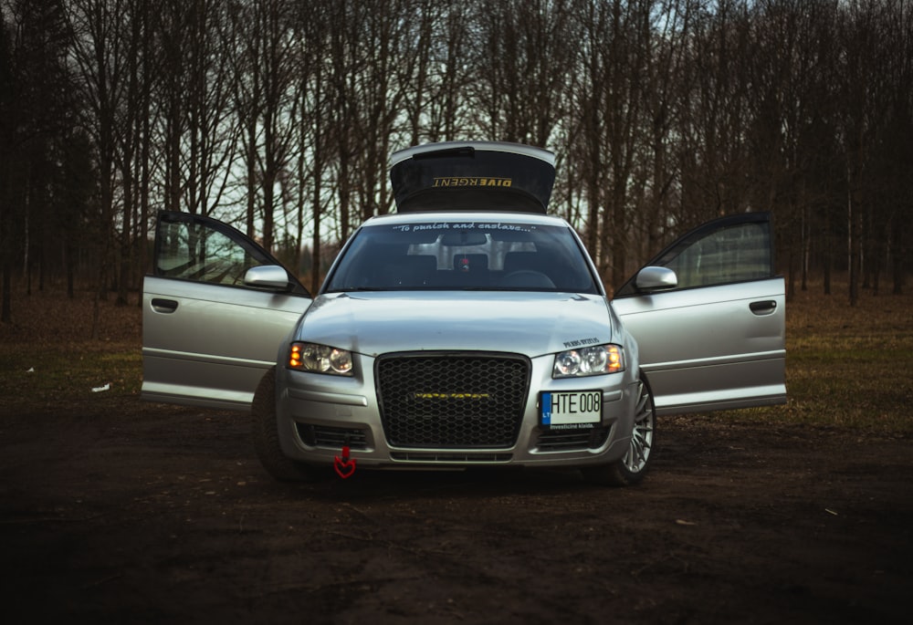 a silver car parked in front of a forest