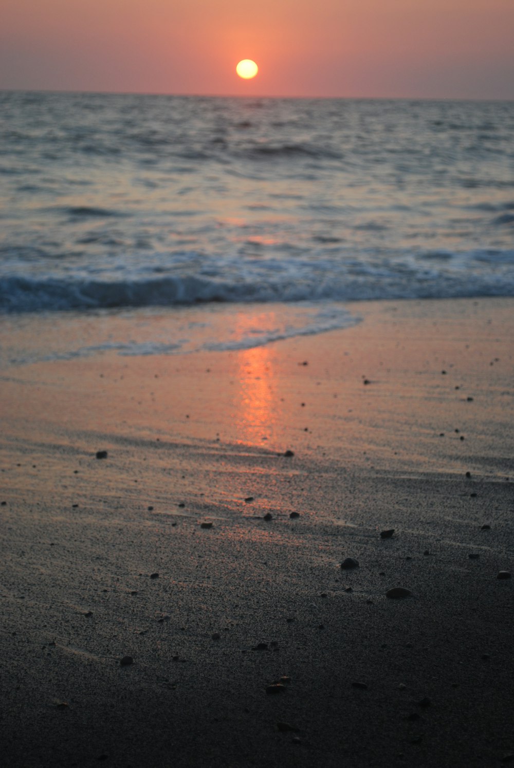 the sun is setting over the ocean on the beach