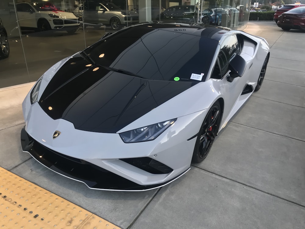 Un coche deportivo blanco y negro aparcado frente a un edificio