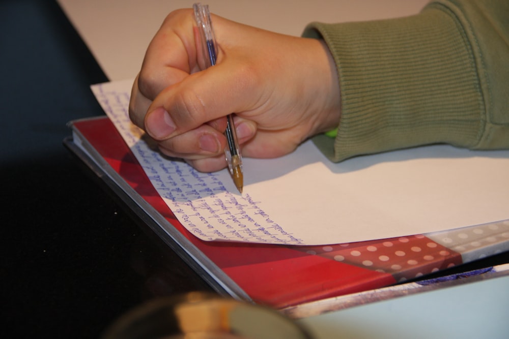 a person writing on a piece of paper with a pen