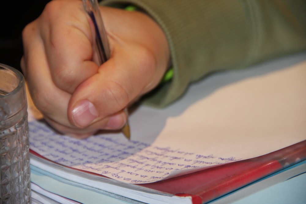 a person writing on a piece of paper with a pen