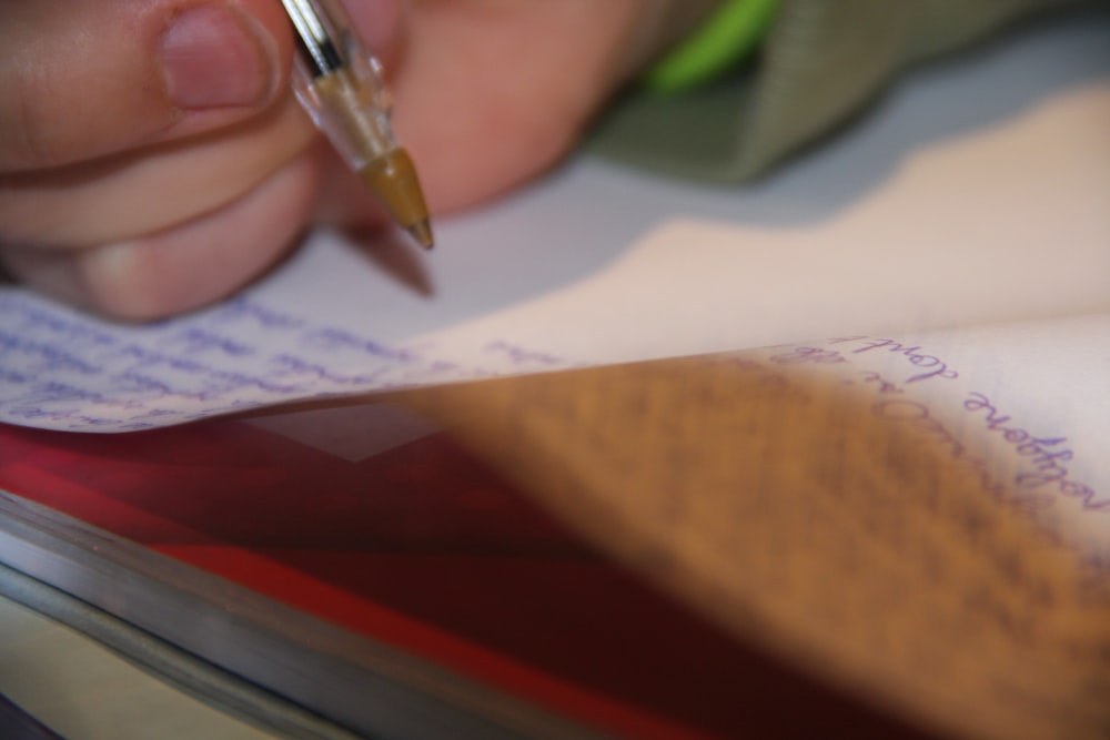 a person writing on a piece of paper with a pen