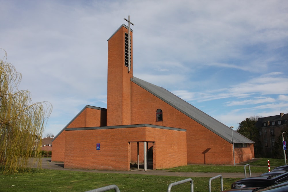 una iglesia de ladrillo rojo con un campanario y una cruz en la parte superior