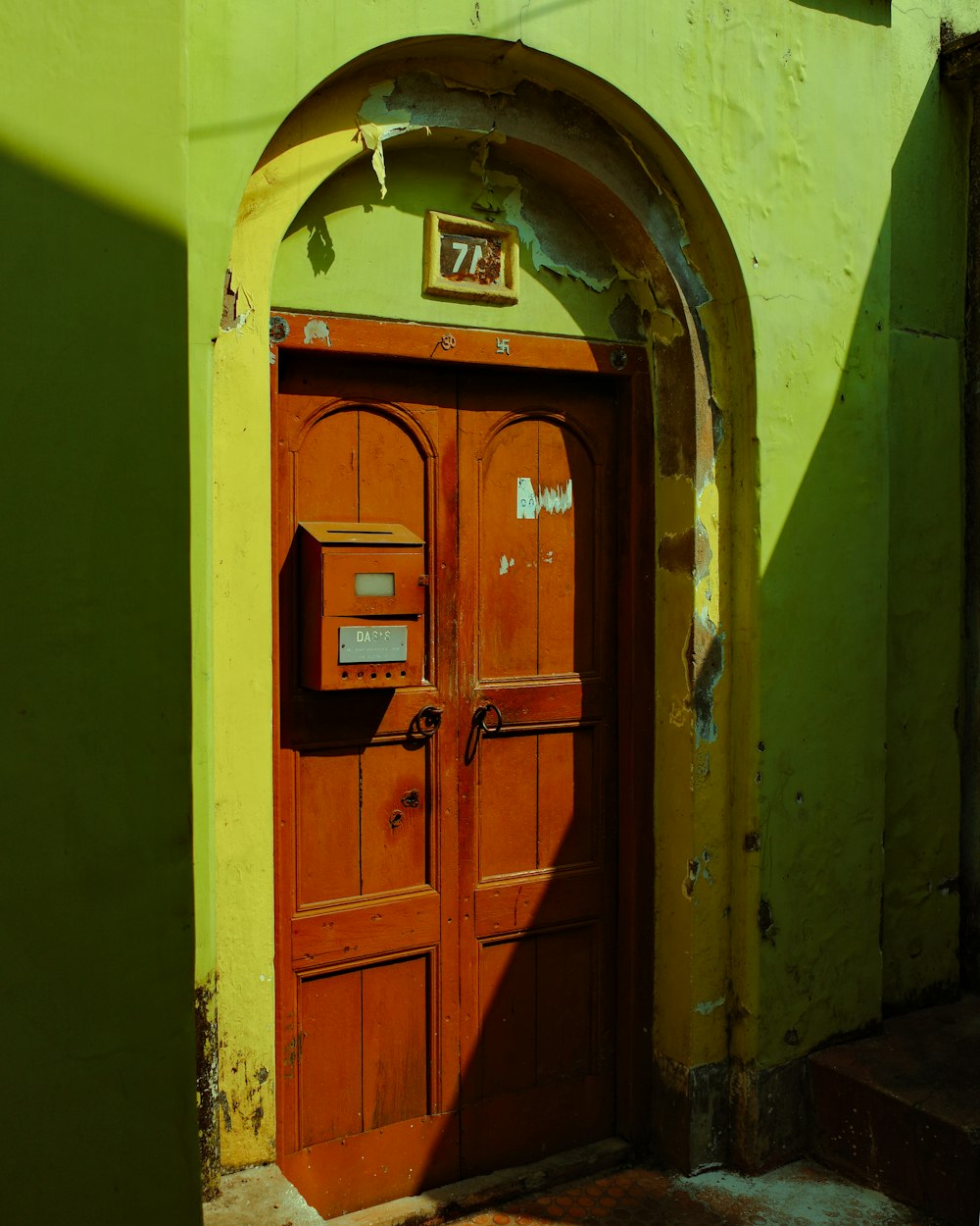 a red door with a sign on it in front of a green building