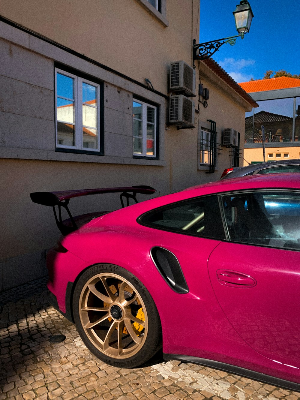 a pink sports car parked in front of a building