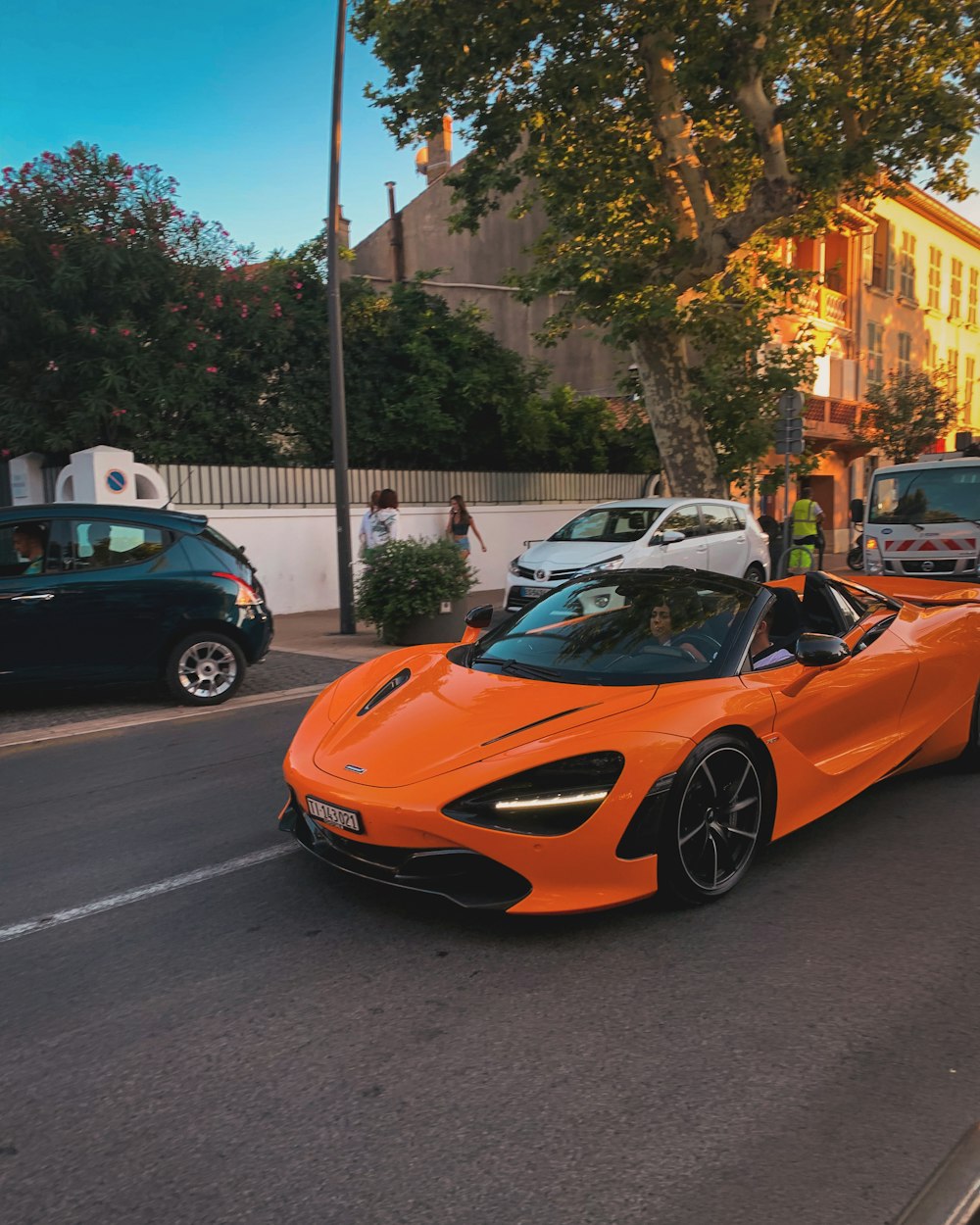 an orange sports car driving down a street