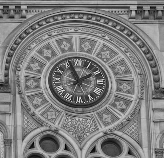 a black and white photo of a clock on the side of a building